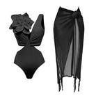 Black swimsuit with cut out side detailing & a 3d black large flower applique featured on the shoulder. Matched with a black mesh rose corsarge detailed on  midi- maxi beach skirt 